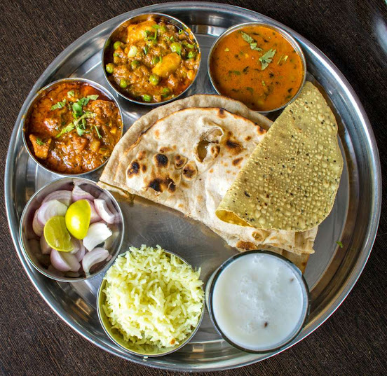Traditional Indian home-cooked thali with roti, dal, vegetables, curd, and rice served on a steel plate