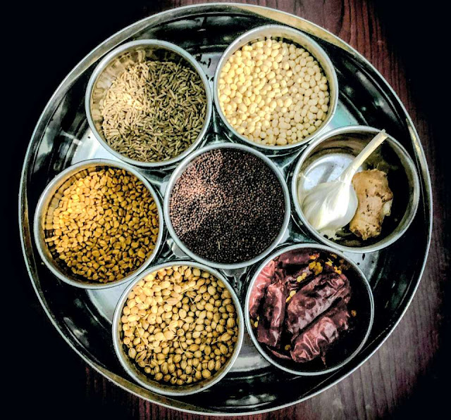 Traditional Indian masala dabba with cumin, mustard seeds, lentils, dried chilies, and ground spices