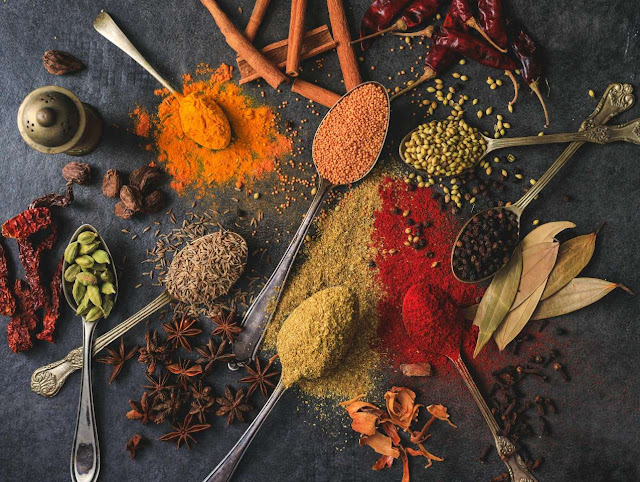 Assorted Indian spices like turmeric, cumin, coriander, and chili powder arranged on a rustic surface