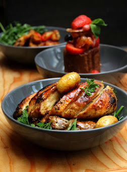 juicy pan seared chicken breast served in bowl with roasted potatoes and herbs